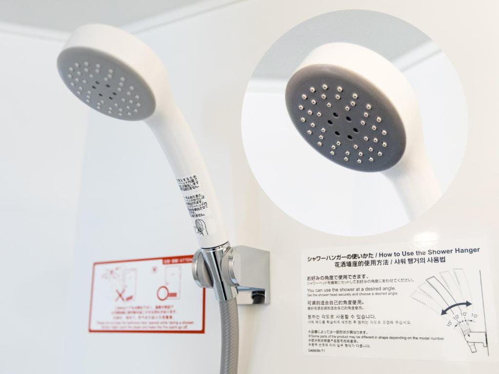 a white toilet with a shower head on a wall at APA Hotel Nishifunabashi Ekimae in Funabashi