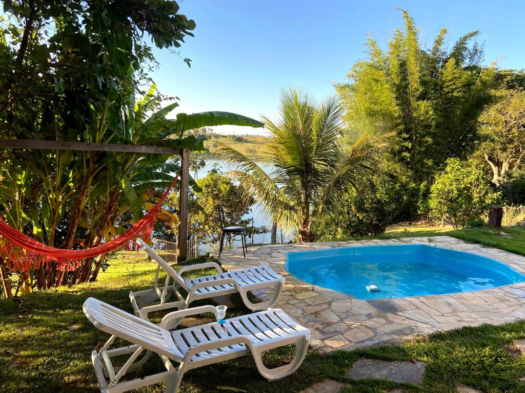 a group of chairs next to a swimming pool at Casa com piscina fundo pra represa e AR Condicionado CasinhaBrancaDeVaranda in Ijaci