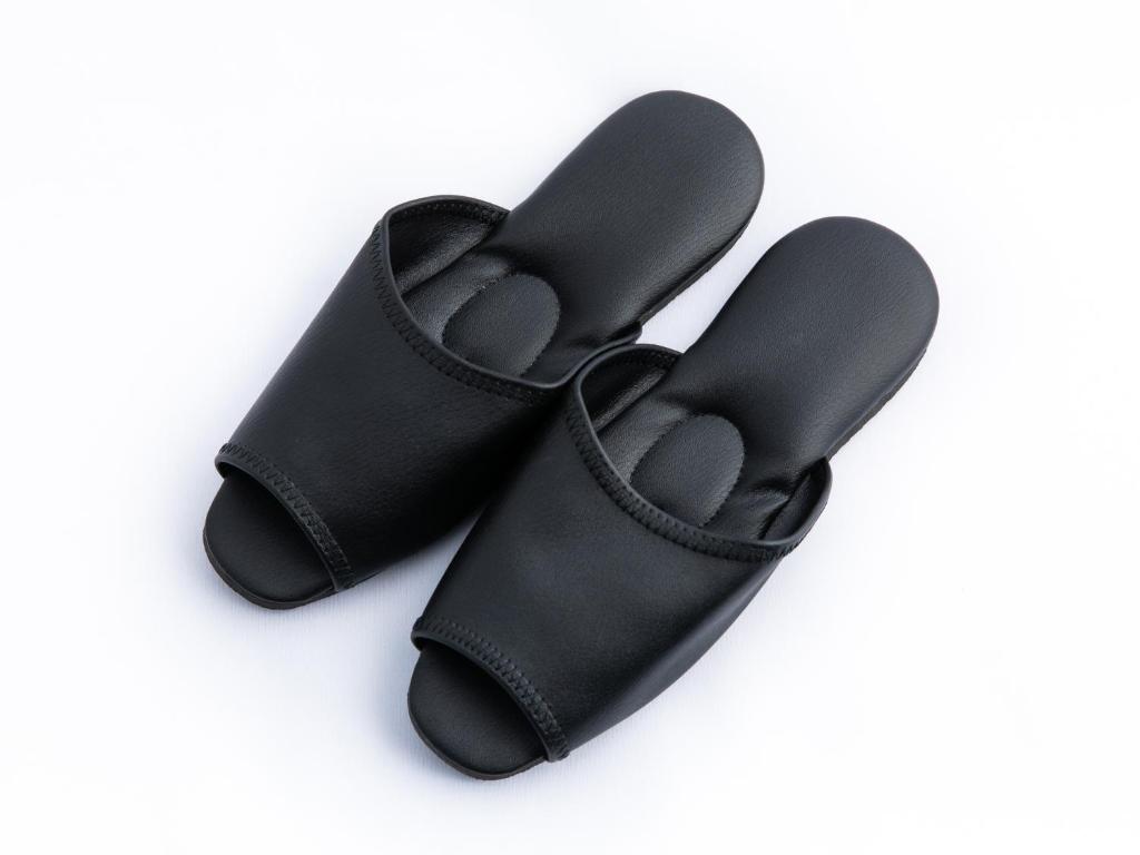 a pair of black slippers on a white background at APA Hotel Nishifunabashi Ekimae in Funabashi