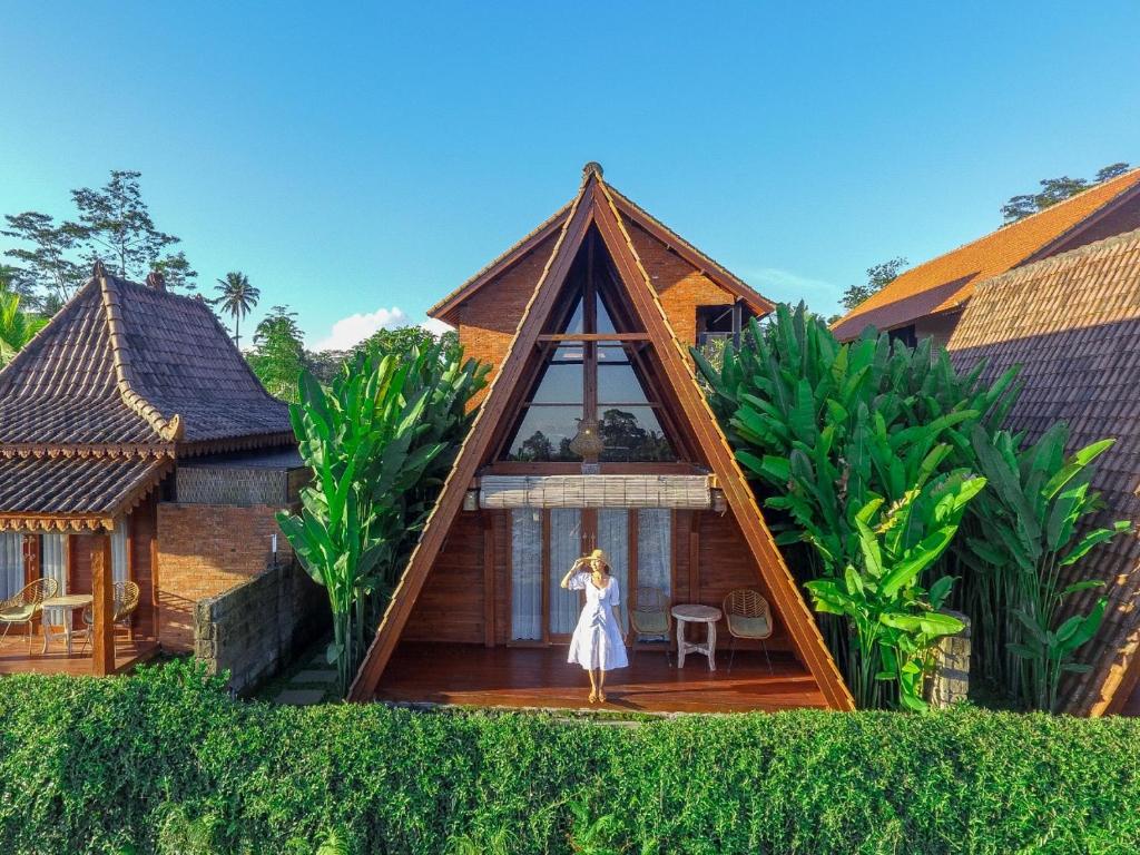 une femme debout devant une maison dans l'établissement Alam Kawi Ubud Resort & Spa, à Gianyar