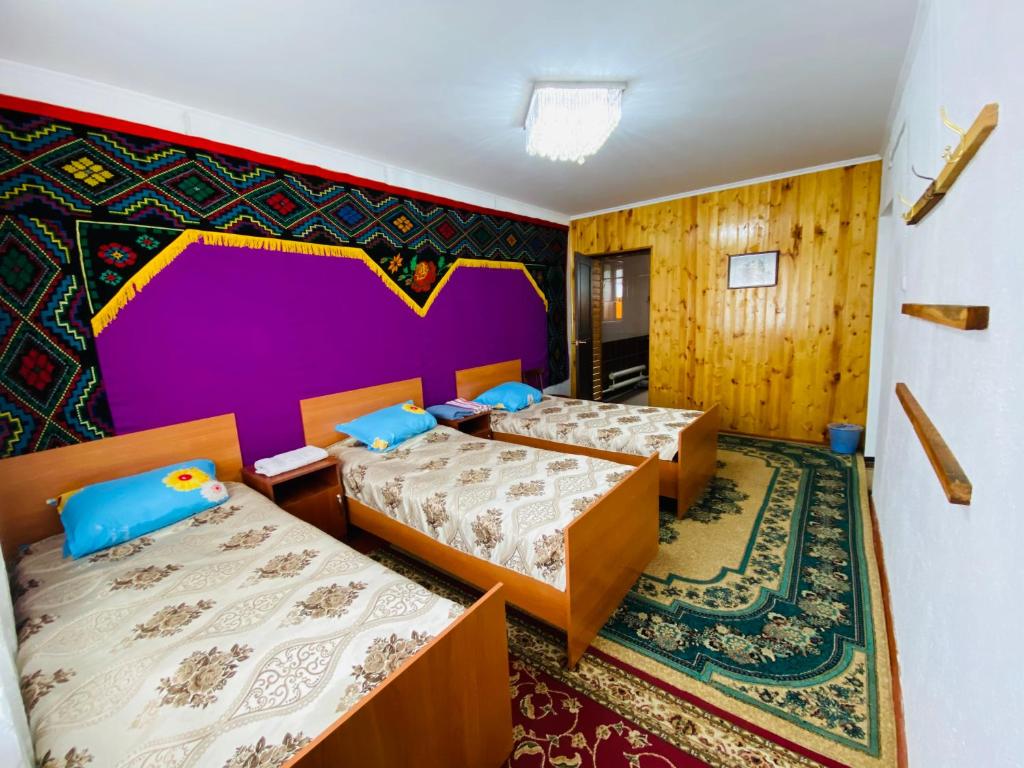 a room with three beds and a colorful wall at Guest House KAGAN in Toktogul