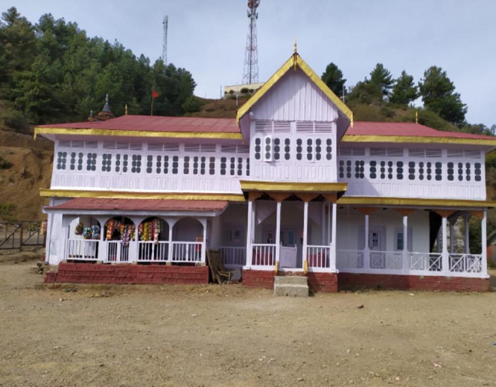 a large white building with a red at Madhan Palace Homestay in Dharmpur