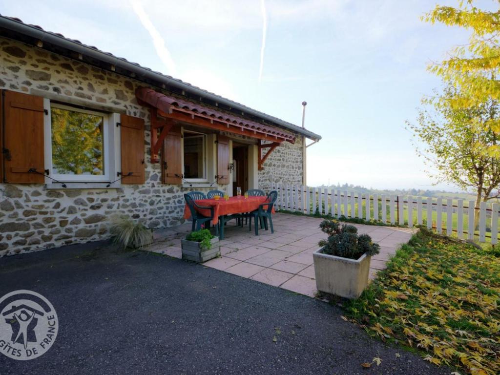 a house with a red table and chairs on a patio at Gîte Saint-Héand, 3 pièces, 4 personnes - FR-1-496-130 in Saint-Héand