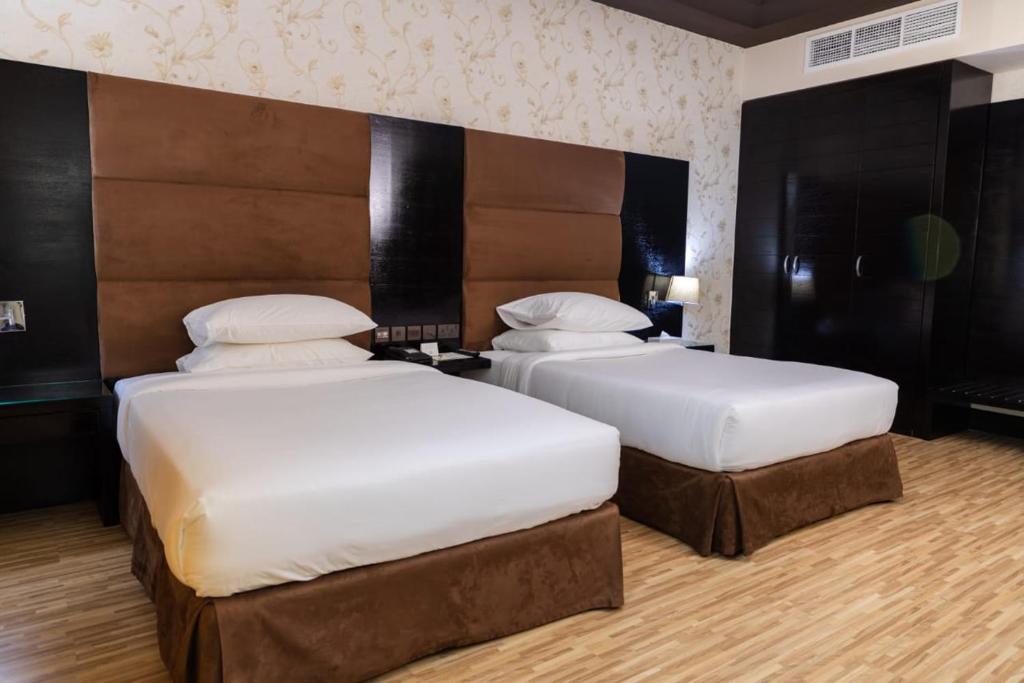 two beds in a hotel room with white pillows at Mangrove Hotel in Ras al Khaimah