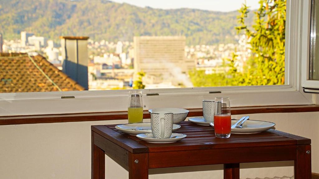 a table with plates and drinks on a table in front of a window at HELVETIA 2 Zimmer Apartment mit Parkplatz in Zurich