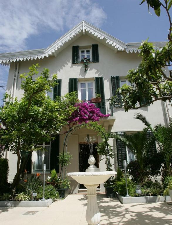 a white house with a fountain in front of it at Hotel Chalet De L'isere in Cannes