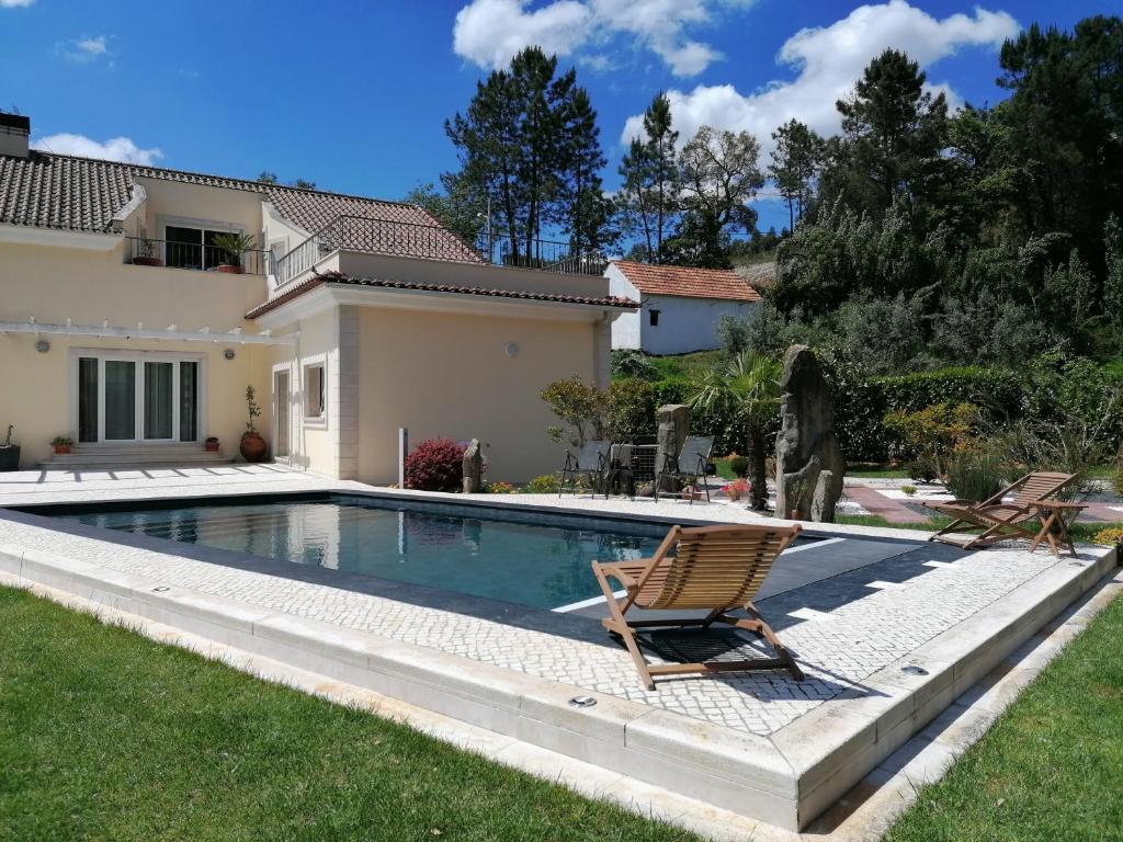 uma piscina com duas cadeiras e uma casa em Cantinho do Lucas em Alvaiázere
