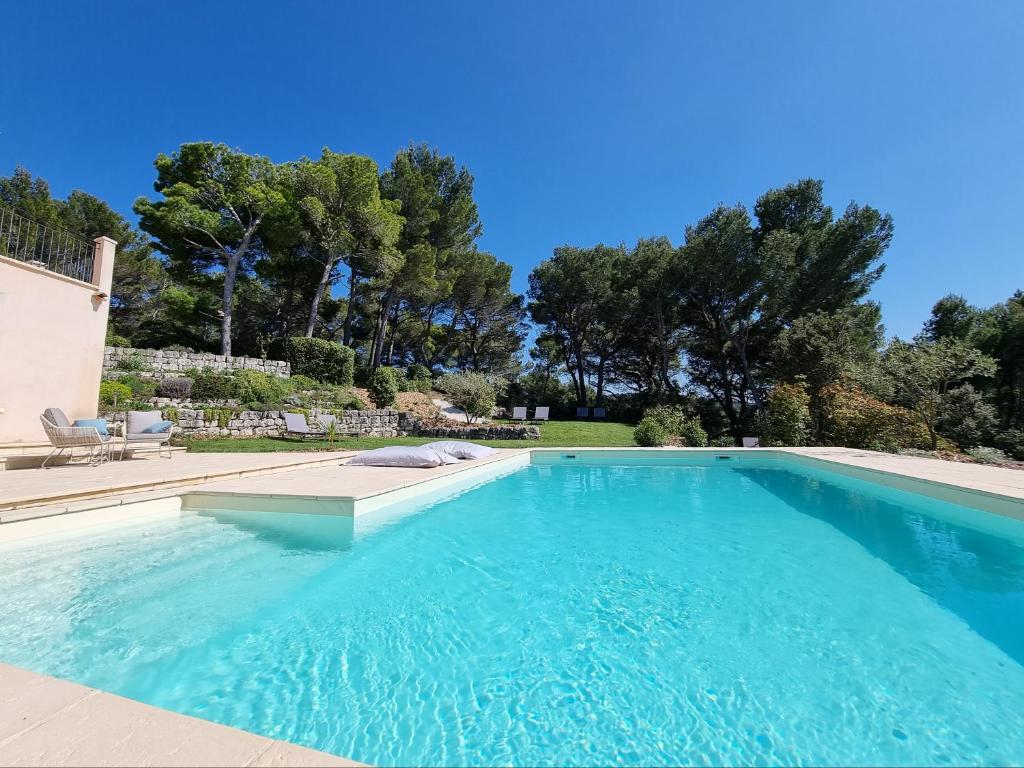 una grande piscina con acqua blu in un cortile di Cosy en Provence - Piscine chauffée de mai à septembre a Pernes-les-Fontaines