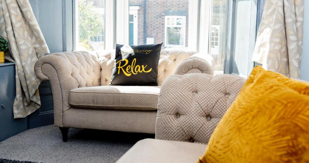 a couch with a pillow with the word relax on it at The Bishophill Gathering York - Sleeps Up To 12 in York