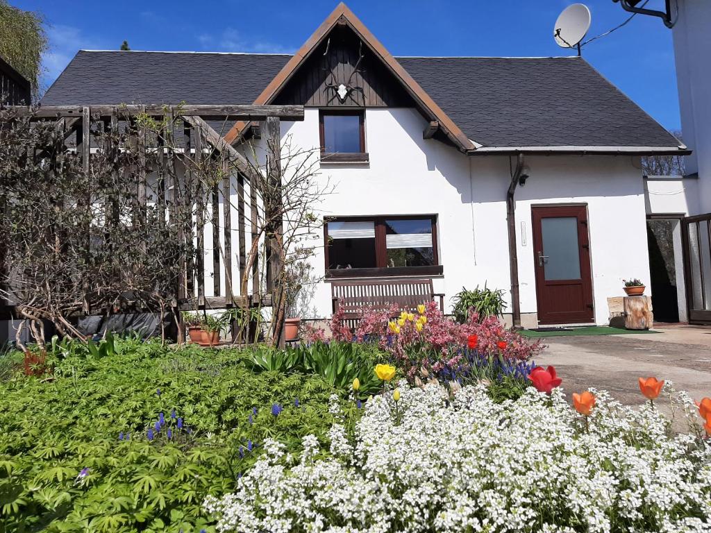 ein weißes Haus mit Blumen im Hof in der Unterkunft Ferienhaus Schoene in Hohnstein