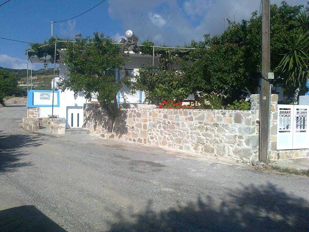 a building with a stone wall next to a street at Dionysia Studios in Kefalos