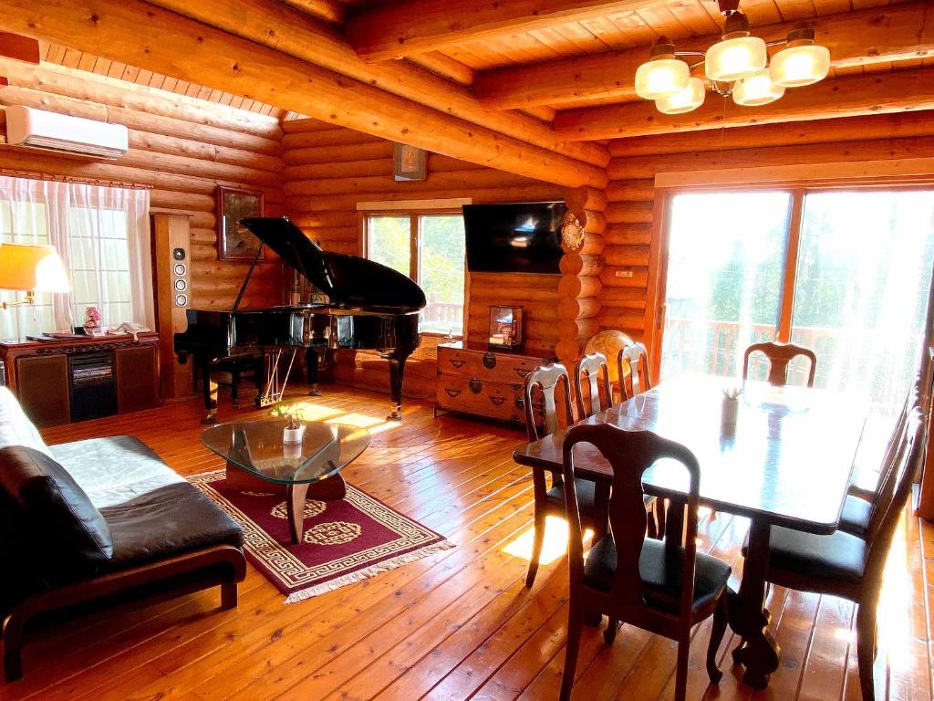 ein Wohnzimmer mit einem Tisch und einem Klavier in der Unterkunft A Private Log House with Mt Fuji View & Piano - "Thangtong House Japan" in Kannami