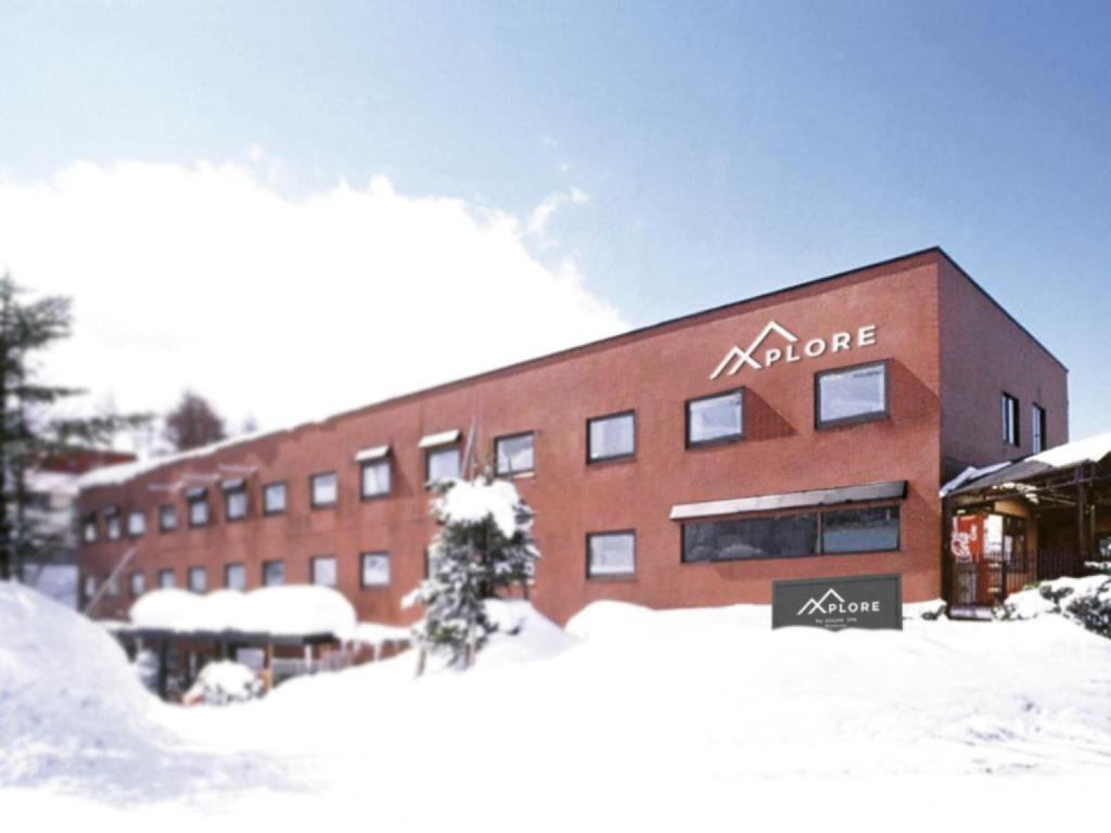 a large brick building with snow in front of it at Xplore by Active Life in Iiyama