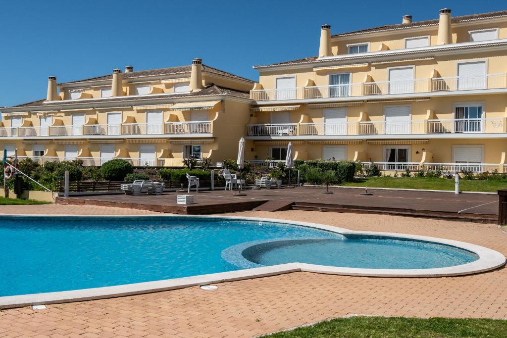 un hotel con piscina frente a un edificio en Casa da Praia, en Ericeira