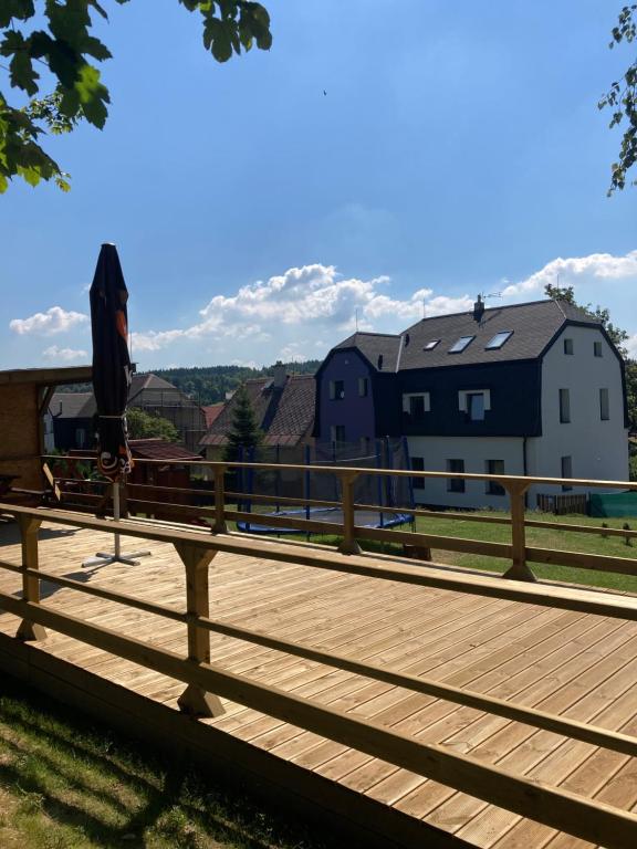 een houten terras met een huis op de achtergrond bij Apartments Villa Viola in Kovářská