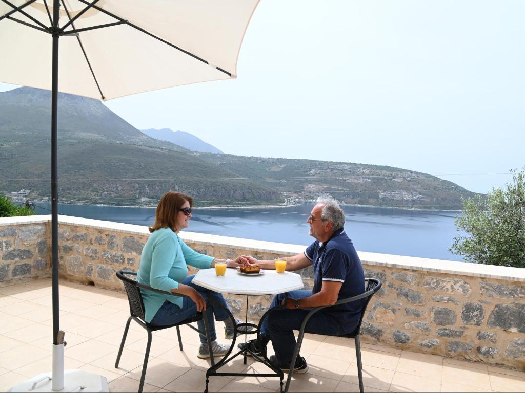 a man and woman sitting at a table under an umbrella at Selana View in Karavostasi