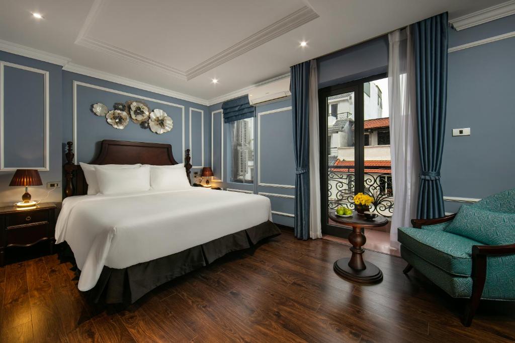 a bedroom with a large bed and a chair at Romantique Hotel De Hanoi in Hanoi