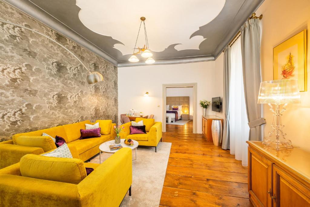 a living room with yellow furniture and a stone wall at Bellevue Hotel Český Krumlov in Český Krumlov