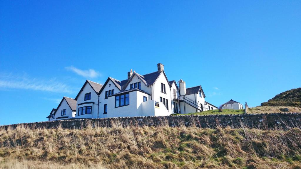 a large white house on top of a hill at Bettyhill Hotel in Bettyhill