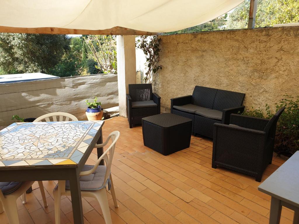 eine möblierte Terrasse mit einem Tisch und Stühlen in der Unterkunft Les Restanques du Sud in Le Lavandou