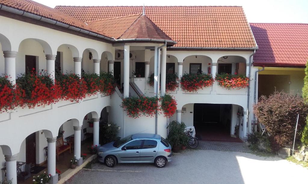 un coche aparcado frente a un edificio con flores en Eden Panzió, en Eger