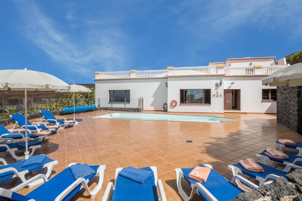 a villa with a swimming pool and blue lounge chairs at Finca Bellavista in Teguise