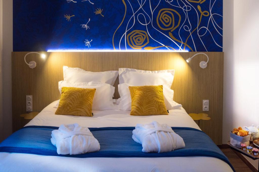 een slaapkamer met een bed met twee handdoeken erop bij Kyriad Prestige Amiens Poulainville - Hotel and Spa in Poulainville