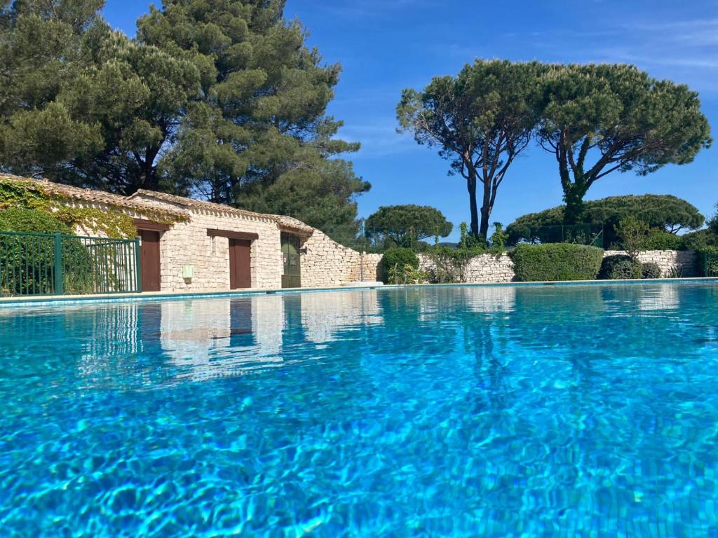 a swimming pool with blue water and trees in the background at AzuRoMarin in Gassin