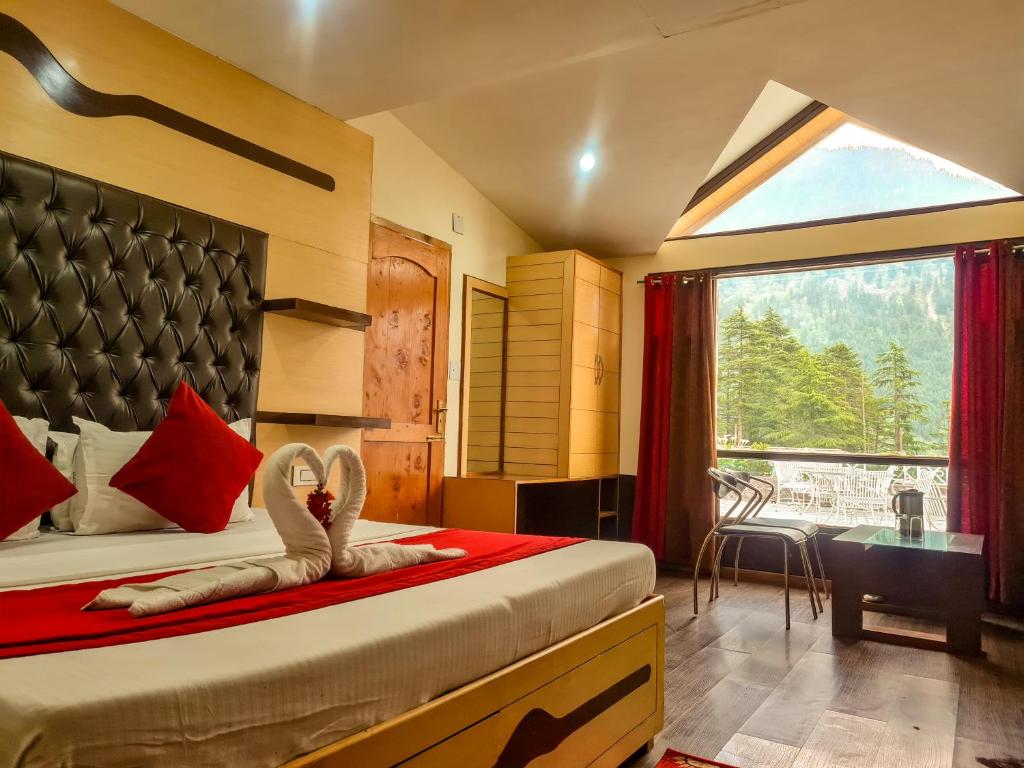 a bedroom with a bed and a window with a view at Hotel Mountain Top in Manāli