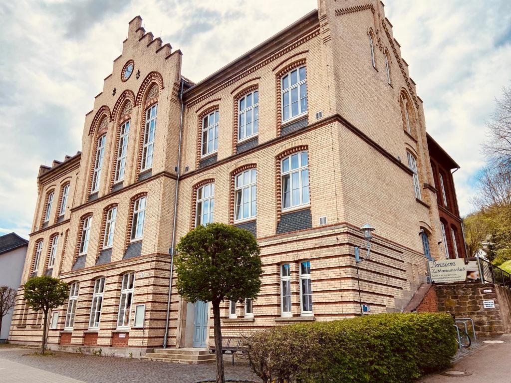 ein großes Backsteingebäude mit einem Uhrturm in der Unterkunft Pension Katharinenschule in Eisenach