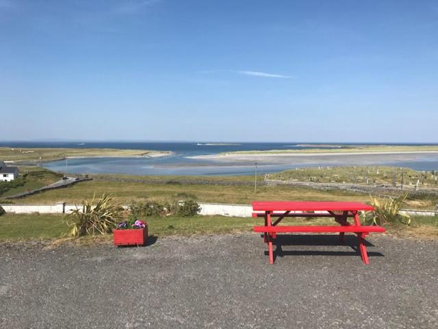 a red bench sitting on top of a sandy beach at Ard Einne House in Inis Mor
