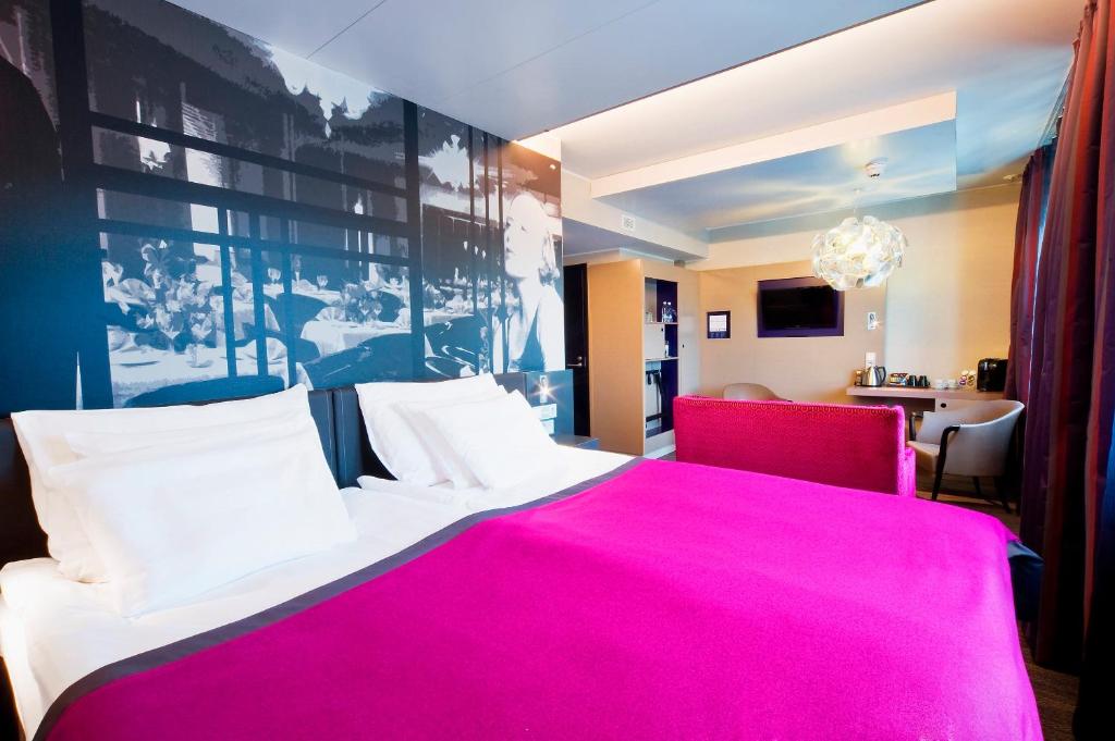 a bedroom with a pink bed with a red chair at Solo Sokos Hotel Lahden Seurahuone in Lahti