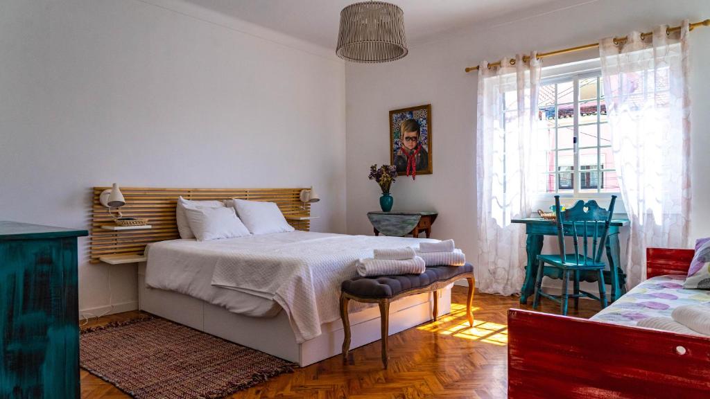 een slaapkamer met een bed, een tafel en een raam bij Mr Ziggy's Surfhouse in Costa da Caparica