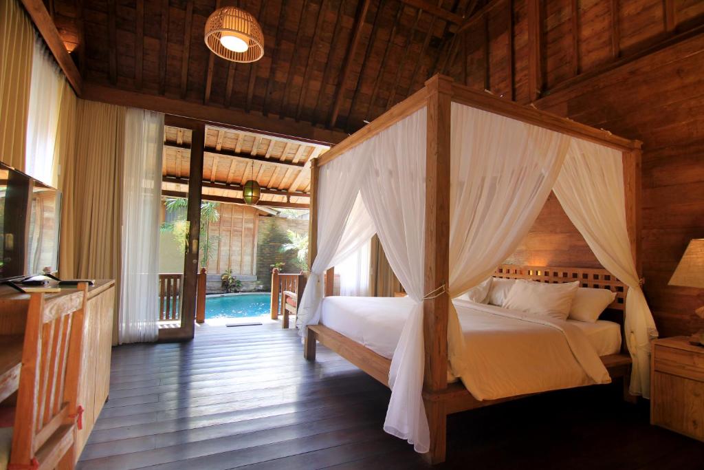 a bedroom with a canopy bed in a house at Taulan Villa by Social Hideout in Kerobokan