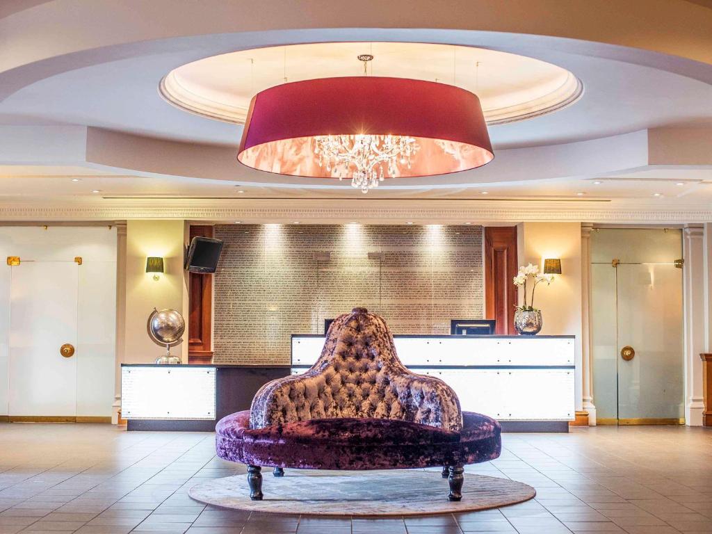 a chair in a lobby with a large ceiling at Mercure Exeter Southgate Hotel in Exeter