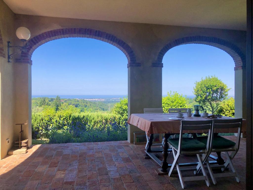 a dining room with a table and two windows at Podere Morena with sea view, private terrace by ToscanaTour Greg in Guardistallo