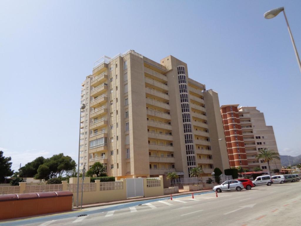 a tall building with cars parked in front of it at Edificio La Reina in Calpe