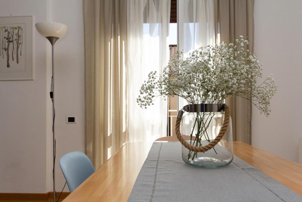 un jarrón lleno de flores sentado en una mesa en Yourbanflat Porta Altinate, en Padua