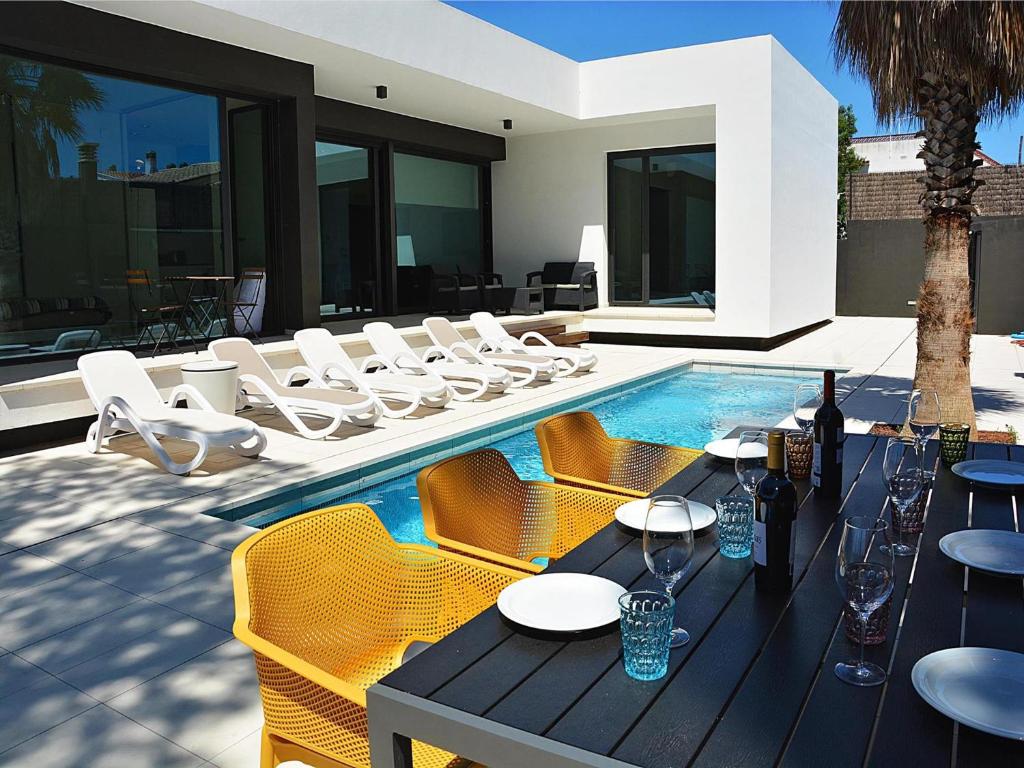 a swimming pool with chairs and a table and a house at Villa Blanca in L'Escala