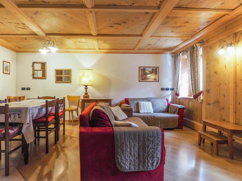 a living room with a red couch and a table at Casa Cristina in Campitello di Fassa