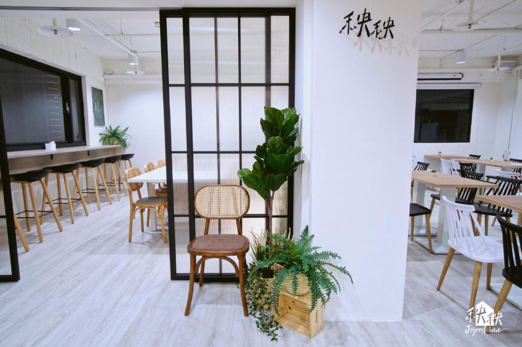 uma sala de jantar com mesas e cadeiras e uma escada em Jezreel Inn em Kaohsiung
