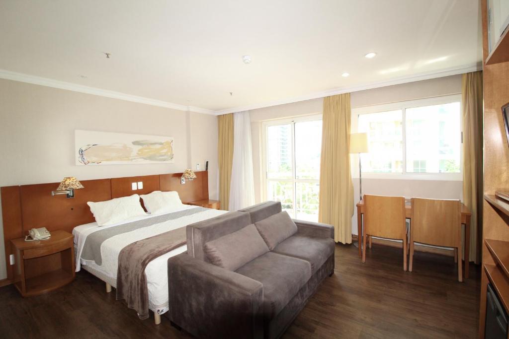 um quarto de hotel com uma cama e um sofá em Pineapples BPremium - Excelentes suítes no Rio de Janeiro