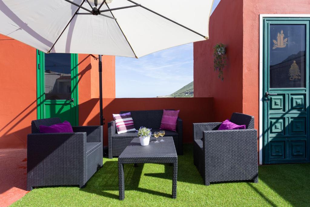 un patio avec des chaises, une table et un parasol dans l'établissement Home2Book Relax Apartment Buenavista, à Buenavista del Norte