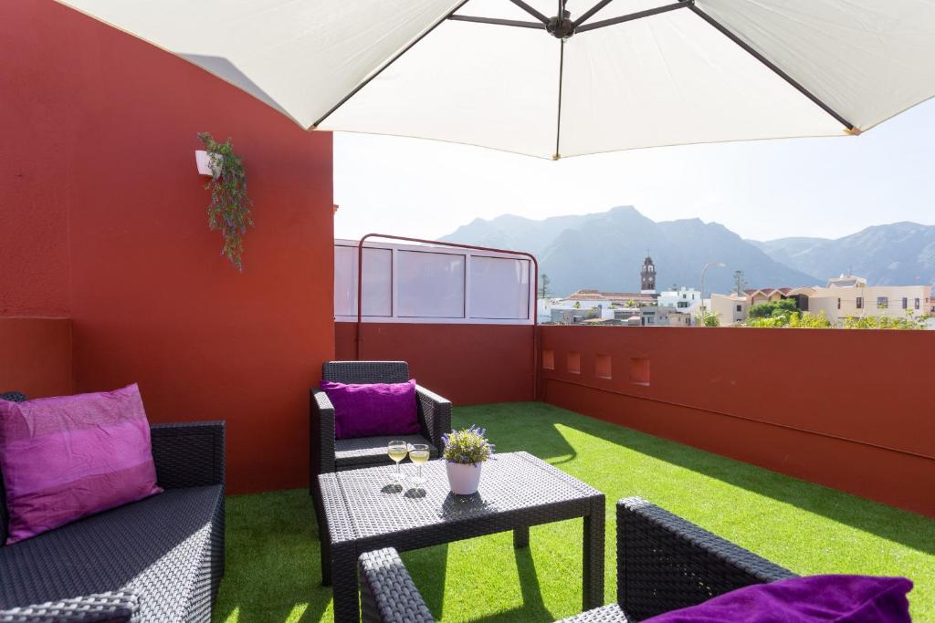 a patio with a table and chairs and an umbrella at Home2Book Relax Apartment Buenavista in Buenavista del Norte