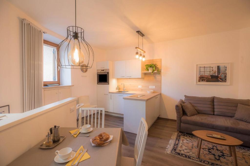 ein Wohnzimmer und eine Küche mit einem Sofa und einem Tisch in der Unterkunft Apartment Eva in Bozen