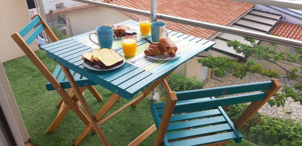 魯瓦揚的住宿－Résidence Nathalie，阳台上的蓝色桌子,上面摆放着面包和橙汁
