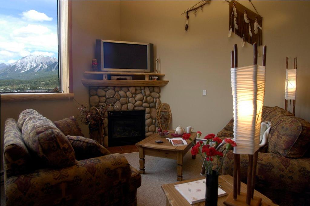 sala de estar con chimenea y TV en Apartment 406, Indigenous Artefacts, en Canmore