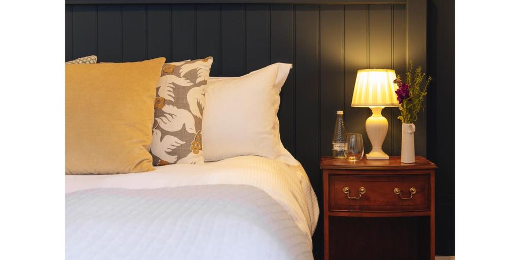 1 dormitorio con cama y mesita de noche con lámpara en The Blue Ball Inn, en Sidmouth