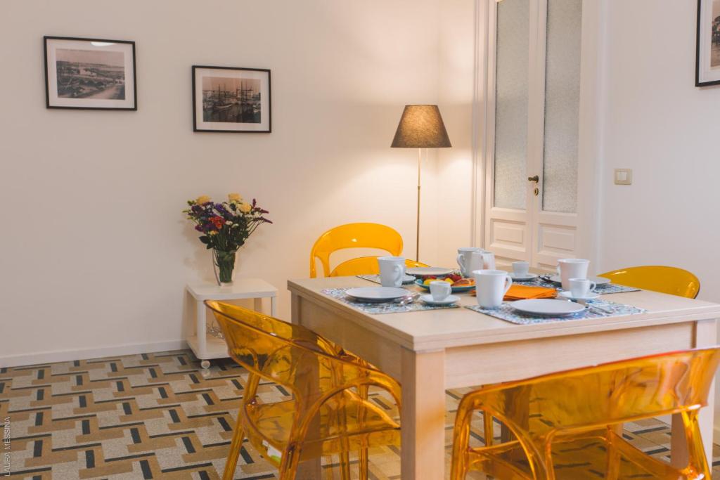 a dining room with a table and yellow chairs at Dimore delle Zagare - Savoia in Siracusa