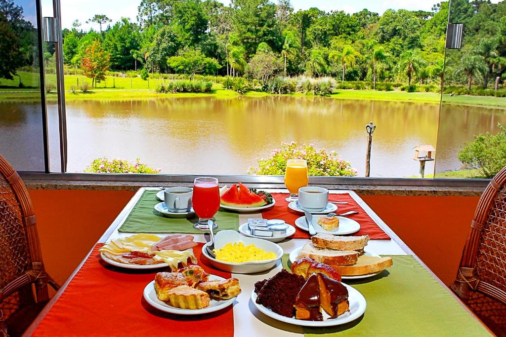 uma mesa com comida para o pequeno-almoço e vista para um lago em Ózera Hotel Fazenda em Prudentópolis